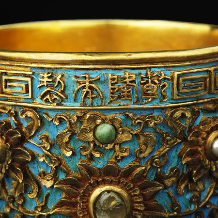 Detail of gold cup decorated with jewels and blue bird feathers