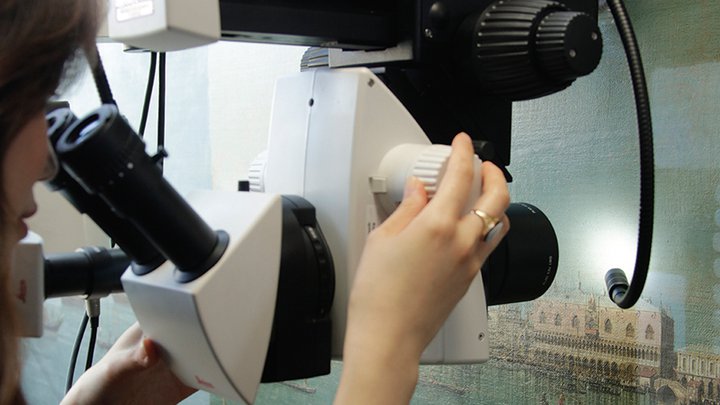 An image of a woman examining a painting