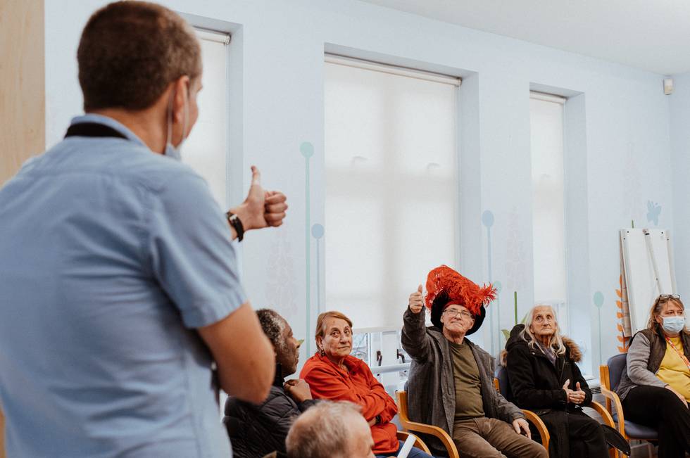 Man talking to a group of older adults, some of them wearing fun costumes